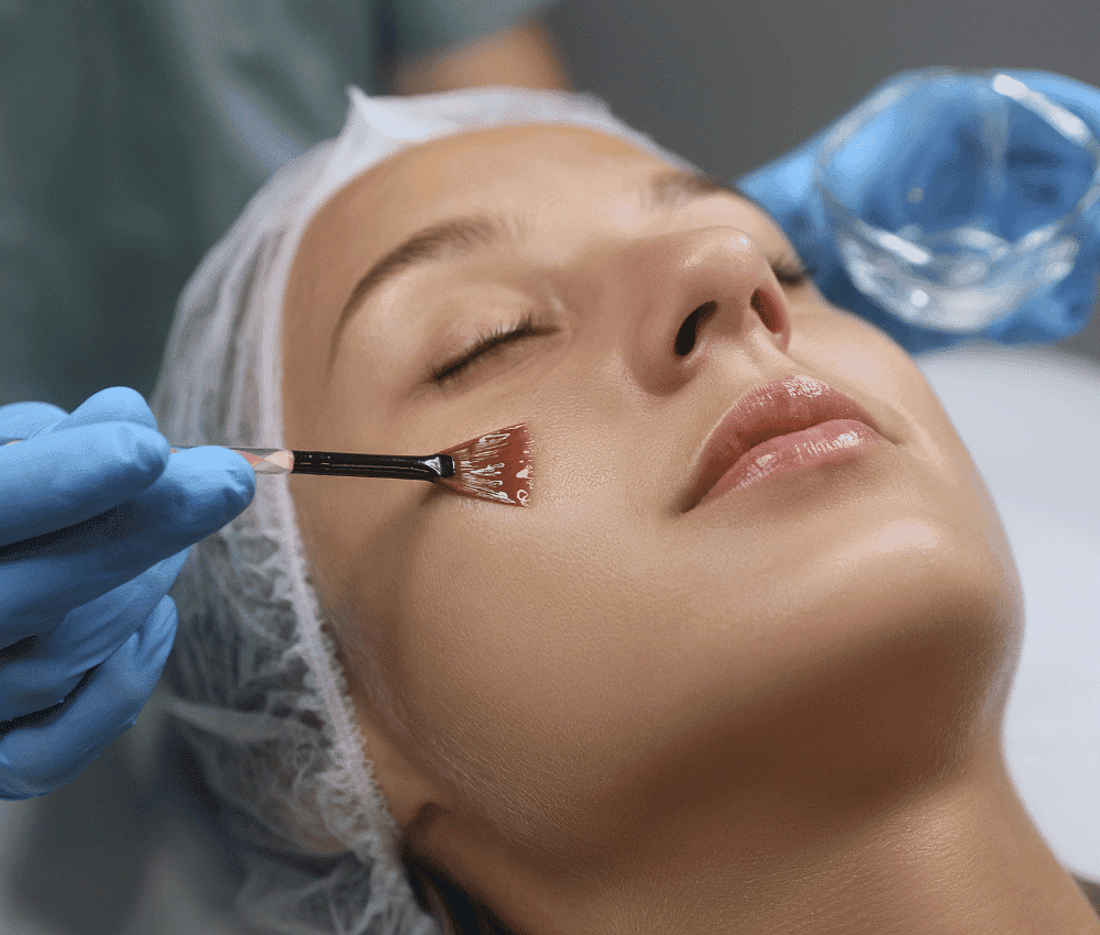Aesthetician applying peel-off mask to woman's face during facial.