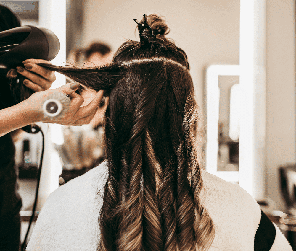 Hairdresser styling a client's hair with a blow dryer.